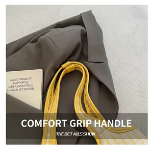 Detailed close-up of yellow leather handles and striped fabric on a stylish tote bag
