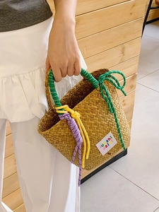 Handmade woven straw beach bag with colorful braided handles and a stylish brand patch
