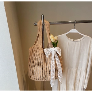 Detail of hand-woven crochet tote bag with elegant white lace bow and floral accent
