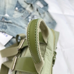 Detail of olive green nylon bag with reinforced handle, white stitching and metal buckle