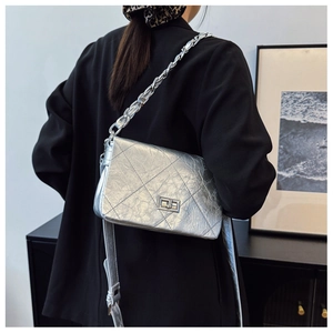 Detail of silver metallic quilted chain bag with turn-lock on a stylish model