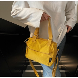Détail du sac bandoulière en nylon jaune avec doubles poignées et poche zippée avant