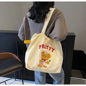 Detail of cream canvas tote bag with red PRETTY embroidery and cute sailor bear design