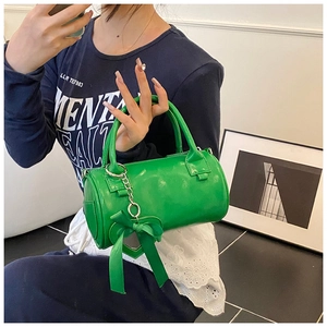 Dettaglio ravvicinato di una borsa cilindrica verde brillante con ciondolo a cuore