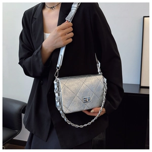 Close-up of silver quilted crossbody bag with metal twist lock and chunky chain detail
