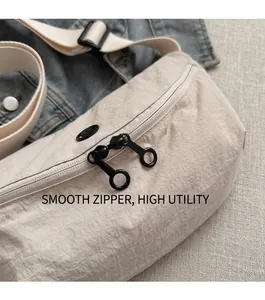 Detail of beige nylon crossbody bag featuring black dual zippers and smooth fabric texture