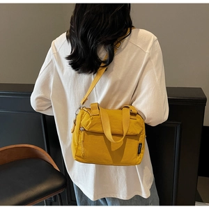 Model wearing a bright yellow nylon crossbody bag with adjustable strap in a minimal room