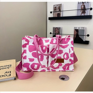 Detail view of pink leopard print tote bag with dual front pockets and leather logo tag