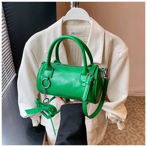 Dettaglio di una borsa Boston cilindrica verde brillante con hardware argento e ciondolo cuore