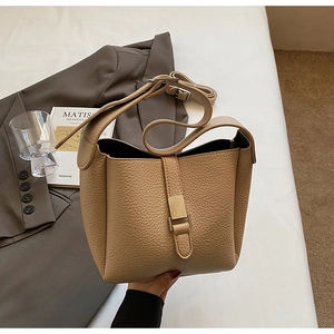 Détail du sac seau en cuir grainé marron clair avec boucle métallique et bandoulière chic