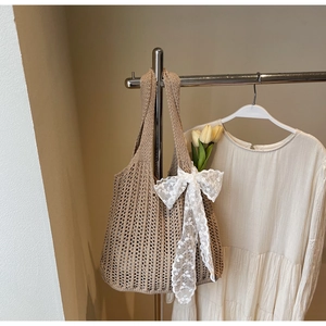 Detailed close-up of a beige crochet tote bag with white lace bow and tulip decoration