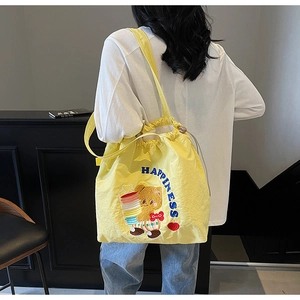 Detail of yellow tote bag featuring cute bear embroidery and drawstring closure