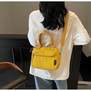 Détail d'un sac à bandoulière en nylon jaune vif avec poche zippée et crochets