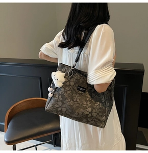 Détail du sac cabas floral sombre avec bandoulière en cuir et charm en peluche nuage blanc