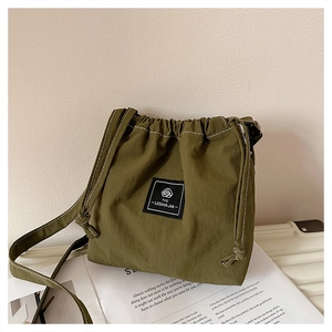 Detail view of olive green drawstring bucket bag with branded label and white topstitching