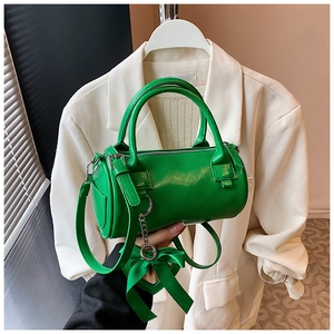 Dettaglio della borsa boston cilindrica verde con finitura lucida e ciondolo in seta
