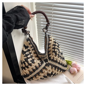 Detail of woven tote bag with wooden bead handle and black geometric crochet pattern
