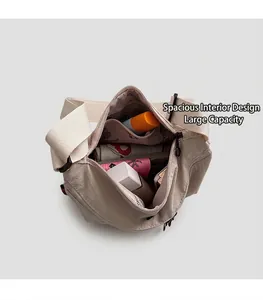 Detail of the spacious interior compartment of this light beige nylon crossbody bag