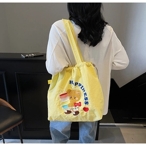Detail of yellow tote bag featuring a cute cartoon bear and a drawstring closure