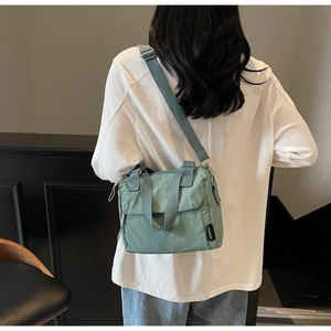 Vue détaillée du sac bandoulière en toile verte avec sangle réglable et poignées