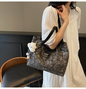 Détail du sac cabas floral avec motifs de trèfles gris et breloque nuage souriant