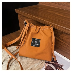 Close-up of caramel drawstring bucket bag with contrast stitching and brand label