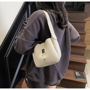 Détail du sac seau en cuir grainé blanc cassé avec bandoulière large et boucle en métal