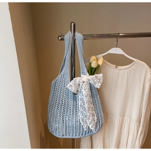 Close-up of light blue crochet mesh tote bag featuring a delicate white lace bow detail