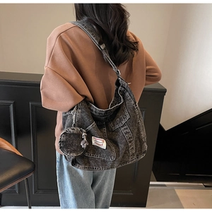 Détail d'un sac cabas en denim noir délavé avec poches et mini porte-monnaie rond