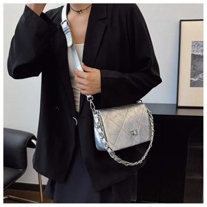 Silver quilted crossbody bag with metallic chain strap shown on a black suit model