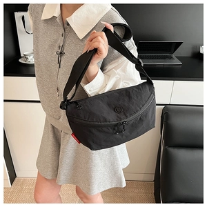 Close-up of lightweight black nylon crossbody bag with dual zippers and adjustable wide strap
