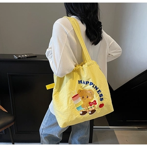 Detailed embroidery of a cartoon bear and blue Happiness text on a yellow nylon tote bag
