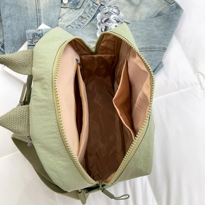 Interior view of bean green nylon backpack showing light brown lining and storage pockets