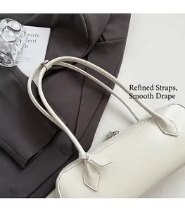 Close-up of cream leather baguette bag with dual shoulder straps on a grey blazer