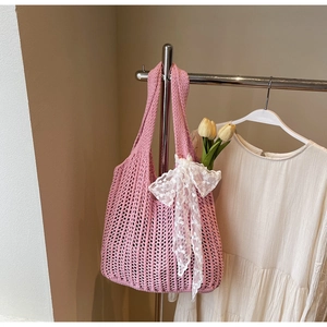 Close-up of pink crochet tote bag with white lace bow and yellow tulip decoration