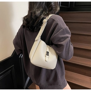 Detailed shot of beige lychee leather bucket bag with silver buckle on model