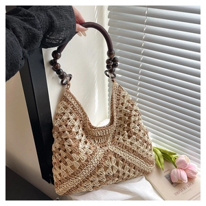 Close-up of woven hollow straw tote bag featuring wooden beads and crochet details