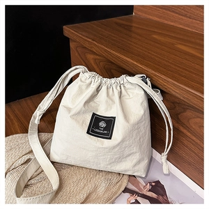 Detail of off-white nylon drawstring bucket bag with black square brand logo patch