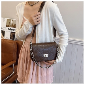 Detail of dark brown quilted crossbody bag with silver twist lock and chain handle