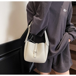 Détail du sac seau en cuir ivoire avec texture grainée et fermoir cadenas métallique