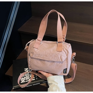 Gros plan du sac bandoulière en nylon rose avec sangle réglable sur des marches
