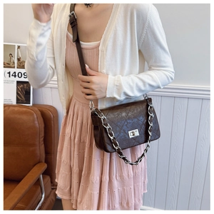 Brown quilted crossbody bag with silver chain strap shown as worn by a model