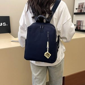 Detail of navy blue nylon backpack worn by a model in a minimalist modern interior