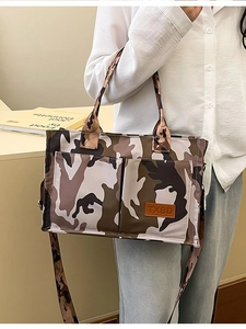 Fashionable camo tote bag with multiple pockets and top handles shown on a model