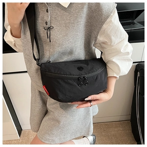 Detail view of durable black nylon crescent bag with dual zippers and woven red side label