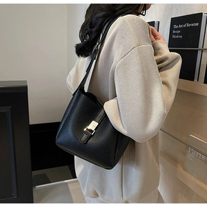 Détail d'un sac seau en cuir grainé noir avec boucle argentée porté par un modèle