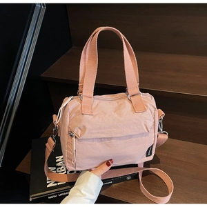 Détail du sac en toile rose clair avec poche zippée et bandoulière sur escalier en bois