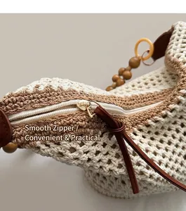 Detailed close-up of smooth metal zipper on a hollow knit bucket bag with wooden beads