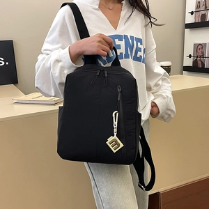Close-up of black fashion backpack with unique vertical zipper and 'm' charm detail