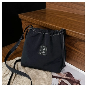 Detail shot of black drawstring bucket bag with logo patch and contrast white stitching